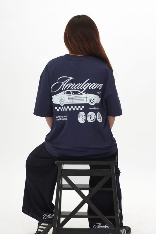 Person wearing a navy blue t-shirt with 'Amalgam' branding on the back, sitting on a black stool against a white background.
Navy Blue Amalgam Overdrive Graphic Tee Oversized Amalgam.store Amalgam
